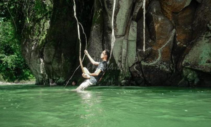 Salah satu pengunjung pemandian Lubuk Asan tampak bersantai sambil bergelantung akar pohon.