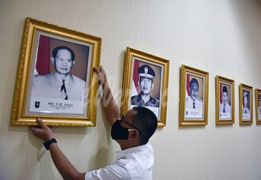 Seorang pegawai merapikan letak foto Gubernur Riau pertama, Sultan Mohammad (SM) Amin Nasution, di Kantor Gubernur Riau, Kota Pekanbaru, Senin (9/11/2020). (antarafoto)