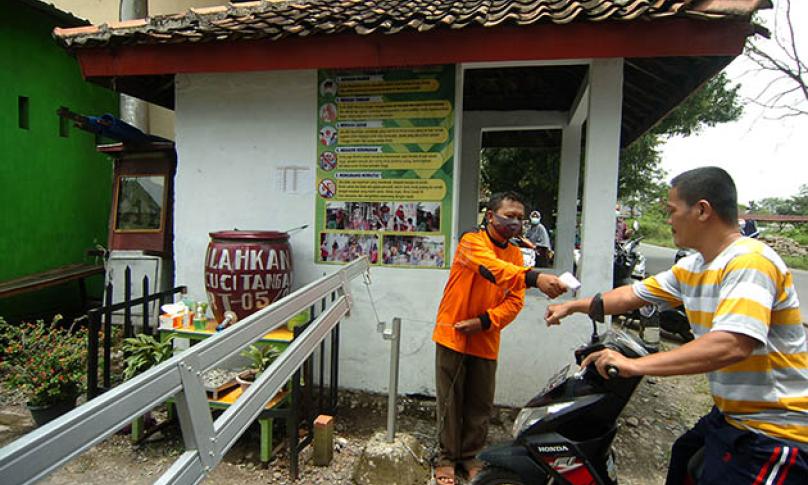Petugas memeriksa suhu tubuh warga sebelum masuk ke kawasan Desa Mindaka, di Kabupaten Tegal, Jawa Tengah, Sabtu (13/3/2021). - (antarafoto)