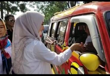 Bupati Luwu Utara, Indah P Indriani sedang membagikan bunga kepada para pengemudi dan sopir angkot. Minggu (1/12).