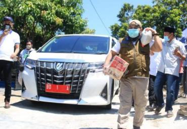 Helmi memikul beras 5 KG dan menenteng 1 dus mie instan terenak di dunia. Helmi langsung menyapanya dengan ramah.