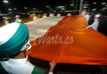 Sejumlah santri membentangkan bendera Merah Putih berukuran besar saat Kirab Merah Putih di Tegal, Jawa Tengah, Senin (17/8/2020) malam. (antarafoto)
