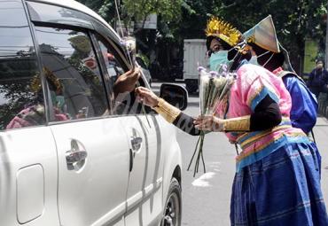 Tenaga kesehatan memakai pakaian adat saat membagikan bunga kepada pengendara di depan RS Siti Hajar Sidoarjo, Jawa Timur, Senin (21/12/2020). (antarafoto)